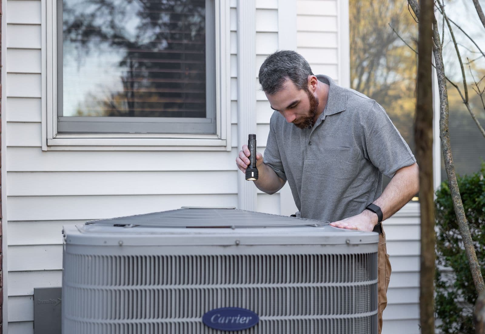 Técnico de HVAC inspeccionando una unidad de aire acondicionado exterior